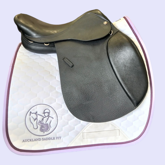 Black leather saddle on a white saddle pad with 'Auckland Saddle Fit' branding.
