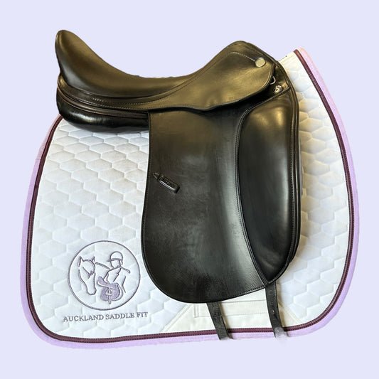 Black leather saddle on a white quilt with 'Auckland Saddle Fit' branding.